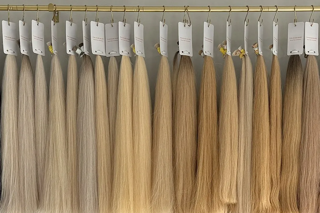 A row of straight Slavic hair bundles, from ash blonde to caramel